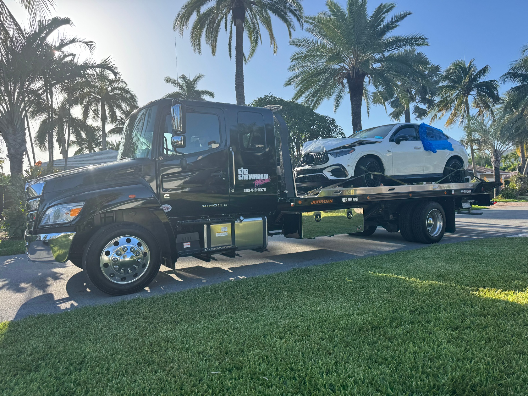 The Showroom Miami professional hydraulic flatbed tow truck transporting a luxury Mercedes-AMG vehicle in Miami